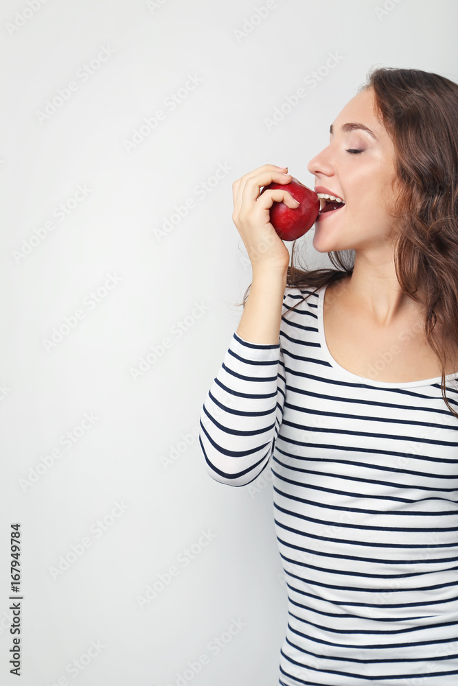 Fototapeta premium Portrait of young woman with apple on grey background