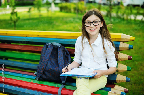 Kid girl doing homework in the park