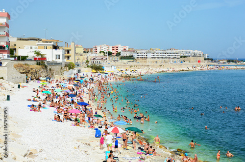 Fototapeta Naklejka Na Ścianę i Meble -  Very Crowded Beach Full Of People At The Mediterranean Sea in Apulia turist region, Bisceglie, Italy