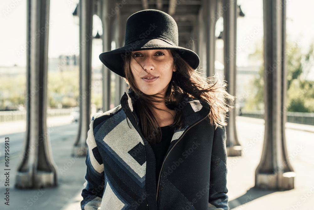 Woman in a hat walking among metal columns Woman in a hat walking among metal columns