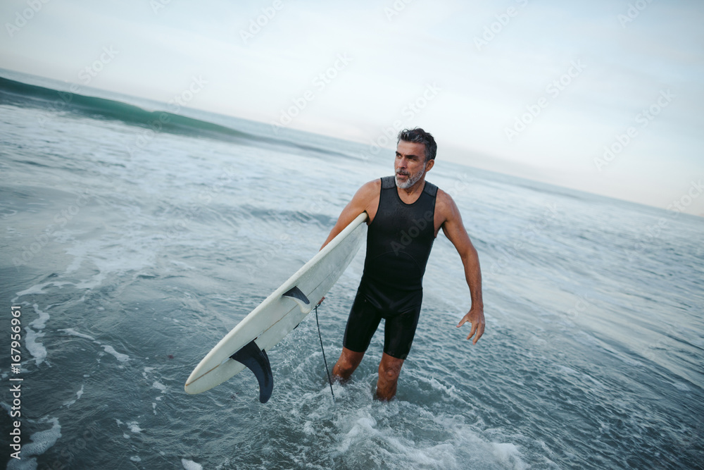 Mature surfer man heading out of the water Mature surfer man heading out of the water