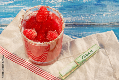 Bright crimson smoothies on a blue wooden background. Raspberry smoothies in a glass cup.Maline cocktail. Natural detoxification. A healthy diet. Liquid ice cream. photo