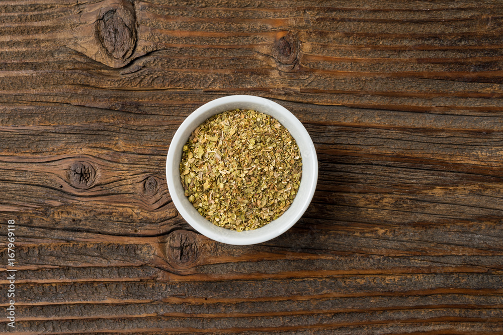 Dried marjoram in white bowl on an old wooden table Dried marjoram in white bowl on an old wooden table