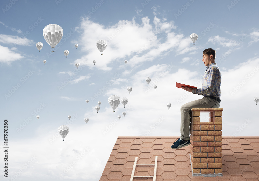 Handsome student guy reading book and aerostats flying in air Handsome student guy reading book and aerostats flying in air