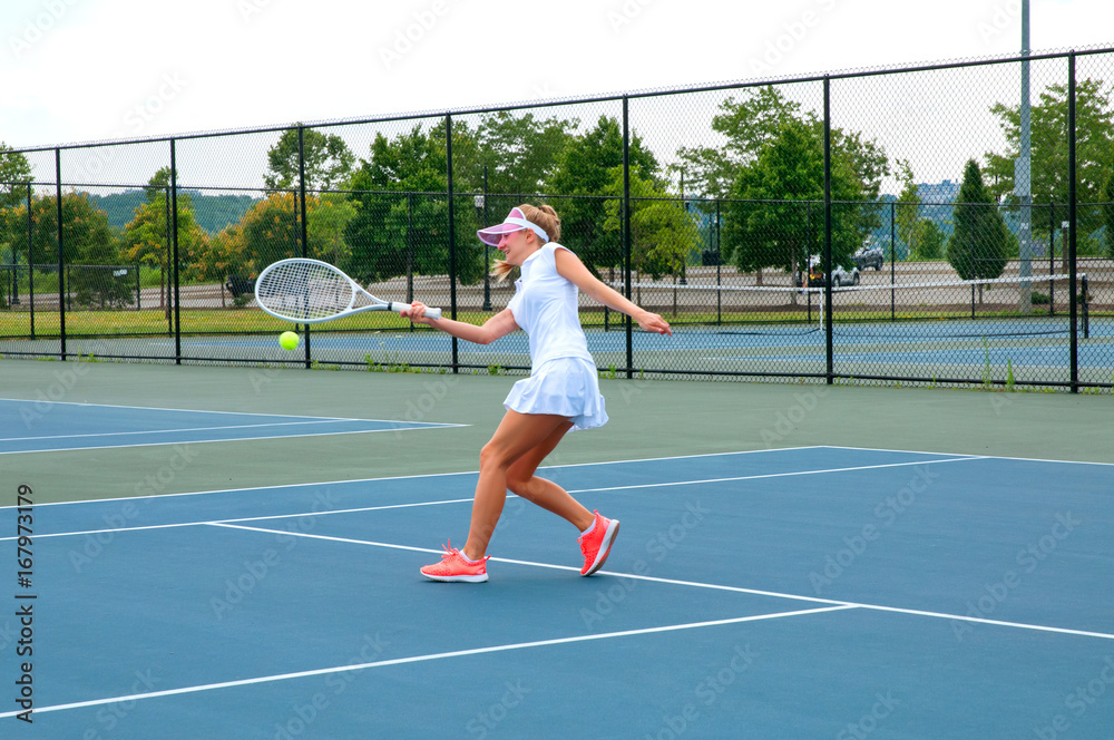 Fototapeta premium Young woman is playing tennis on the tennis court