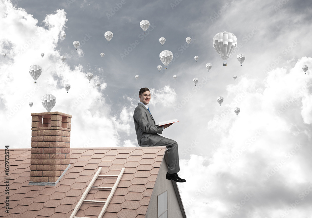 Man on roof reading book and aerostats flying in air Man on roof reading book and aerostats flying in air