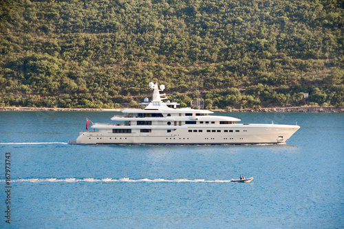 The chain of small boats under tow next to the yacht