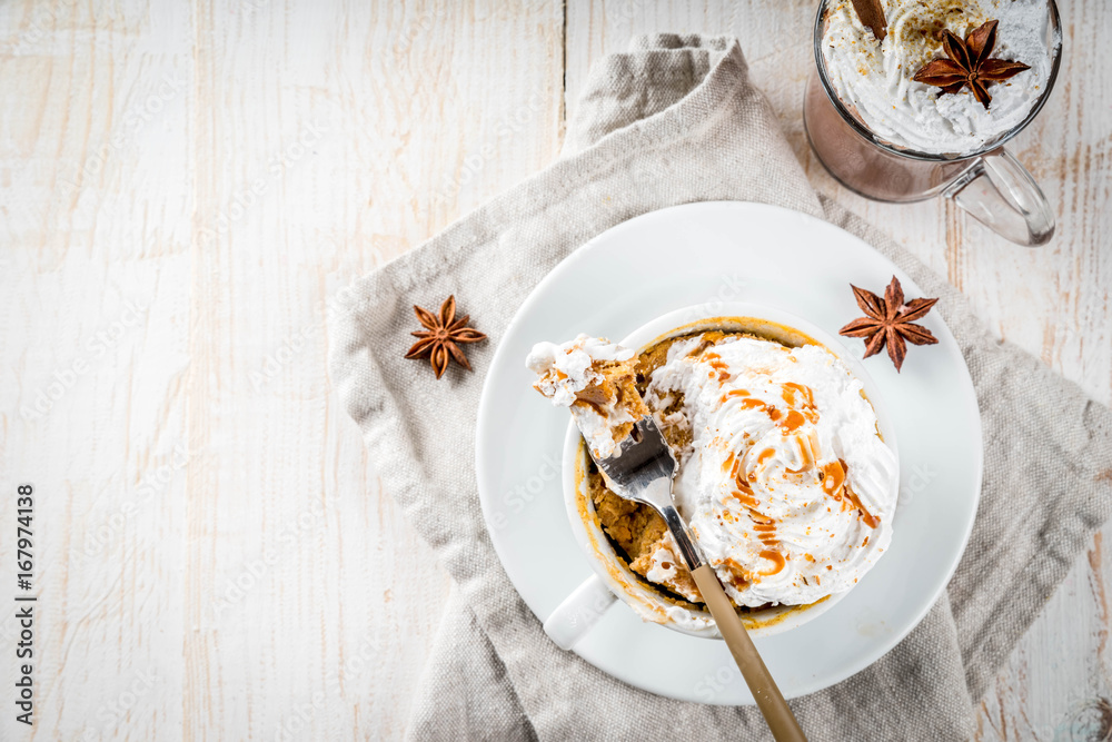Recipes with pumpkins, fast food, microwave meal. Spicy pumpkin pie in mug, with whipped cream, ice cream, cinnamon, anise. On white wooden table, with cup of hot chocolate. Copy space top view