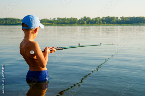 Quadro su tela Boy fishing waist deep in water
