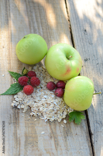 Green apples next to the raspberry with the leaves of gooseberries and a bunch of oatmeal