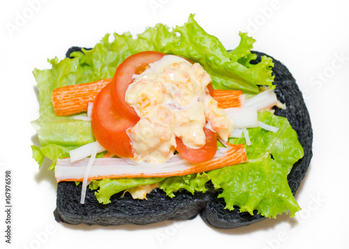 sandwich with lettuce, tomato and crab stick on wood table.