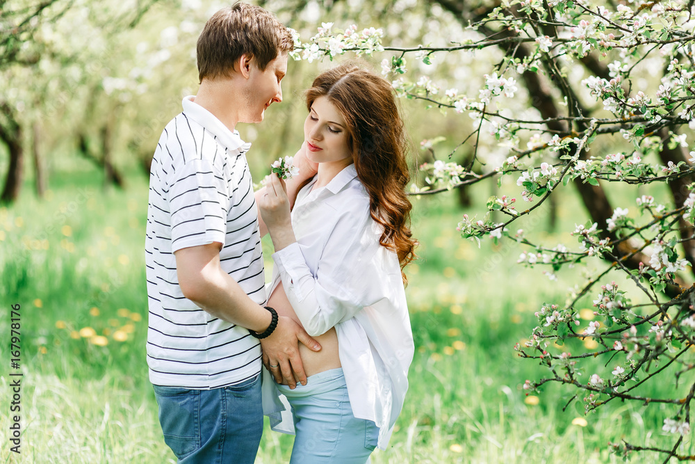 Fototapeta premium Portrait of pretty lovely future parents during sunset on nature apple tree background