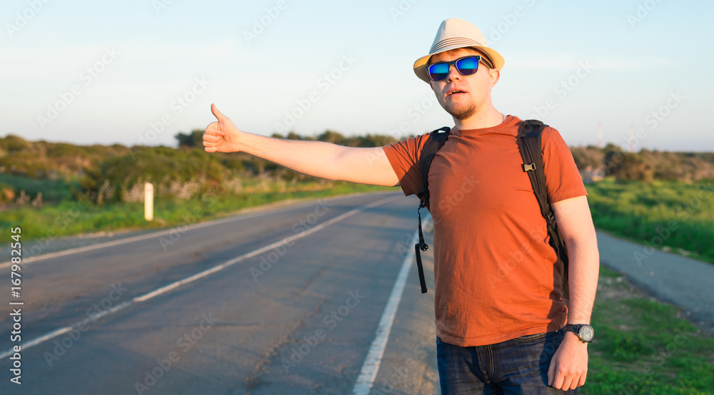Hitchhiking traveler try to stop car on the mountain road.