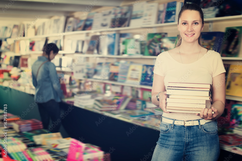 Obraz premium Laughing woman buying books in hard cover