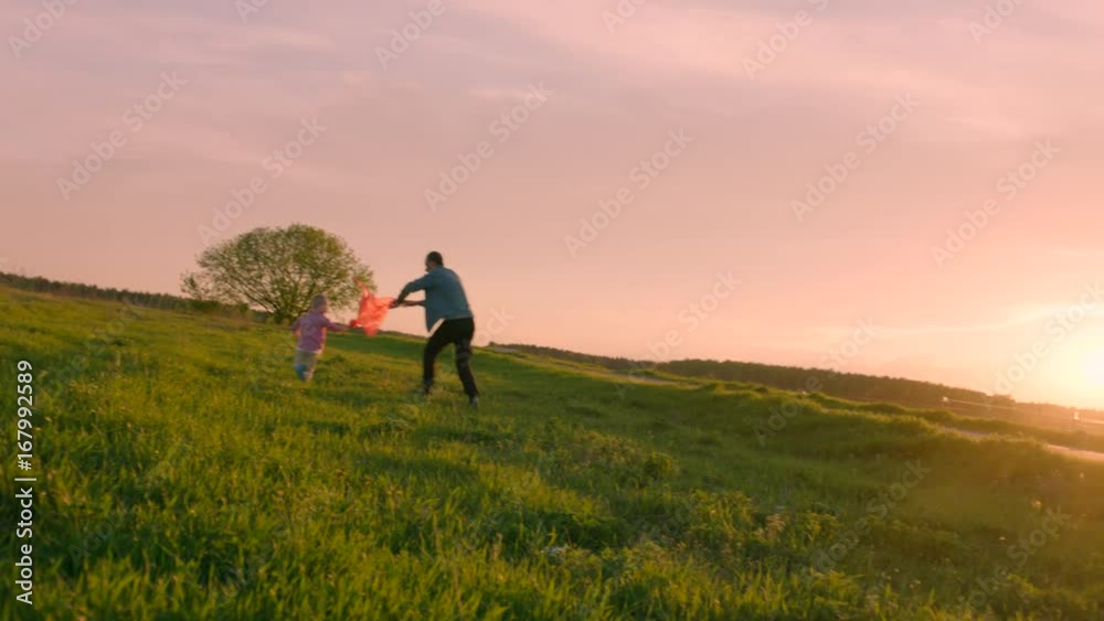 Father and his little son are playing flying kite at sunset Father and his little son are playing flying kite at sunset