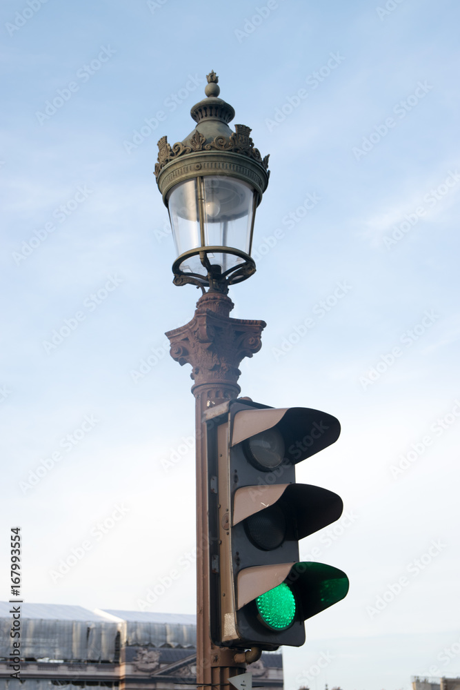 Detail of old street lamp and green semaphore in a street in Paris