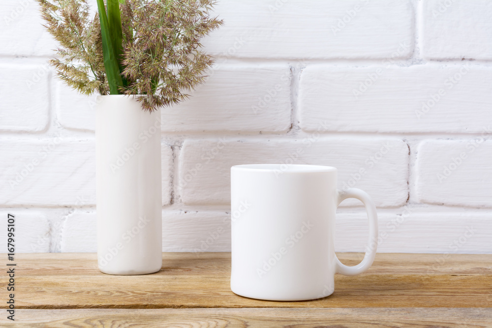 White coffee mug mockup with grass and green leaves in cylinder vase White coffee mug mockup with grass and green leaves in cylinder vase