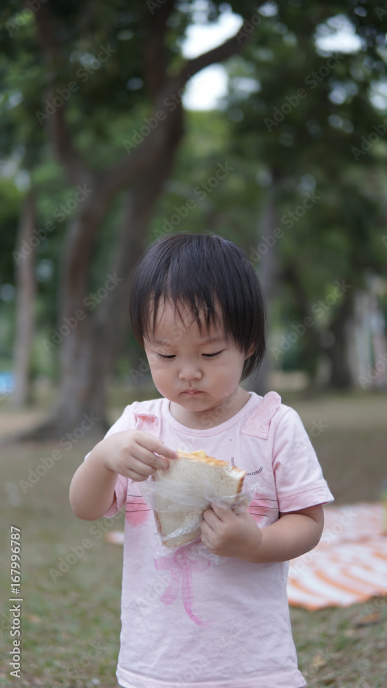 Asian chinese young toddler eating sandwiches by herself Asian chinese young toddler eating sandwiches by herself