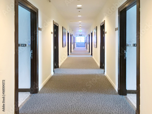 Blurred Corridor with lots of dark brown doors. White walls and ceiling concrete floor. Concept of hotel lobby.
