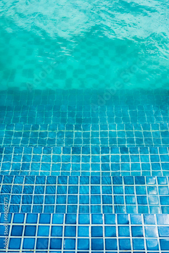 Blue mosaic tiled steps in green swimming pool © oppdowngalon