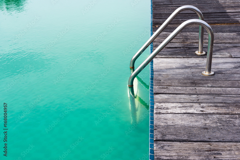 Old steel ladder, wooden floorboards and green swimming pool