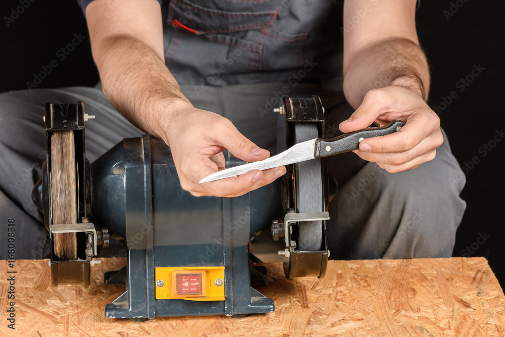 Man in work clothes checks to the sharpness of the kitchen knife on the table