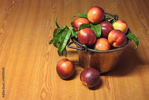 Fresh peaches fruit with leaves in old tray