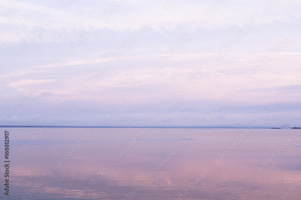 Fototapeta premium A gentle pink sunset on the sea in a calm with a calm water surface and cirrus clouds. Background for the desktop, design and advertising.