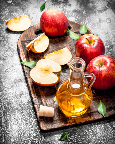 Apple cider vinegar with fresh apples on cutting Board. photo