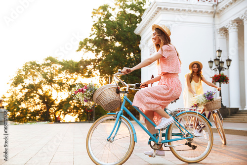 Two pretty smiling girls on a bicycle ride together