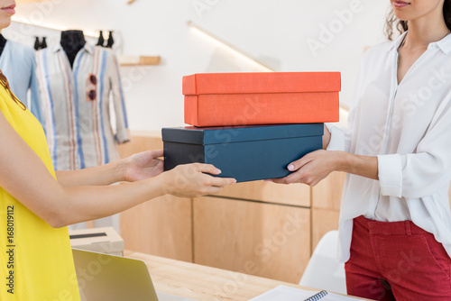 cropped shot of cashier giving shoe boxes to woman