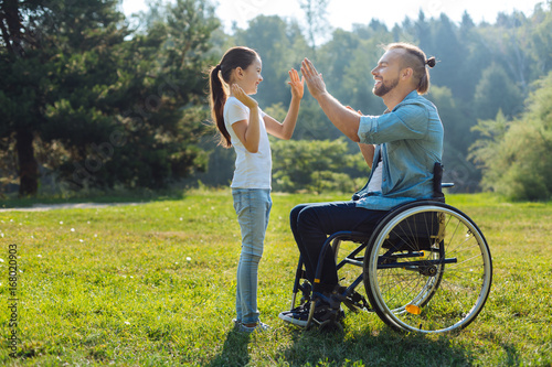 Young father with mobility impairment high-fiving daughter