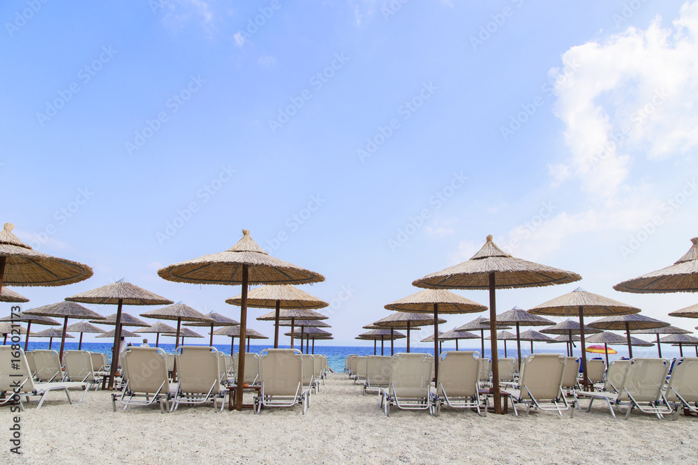 Sun umbrella and beach beds on tropical coastline