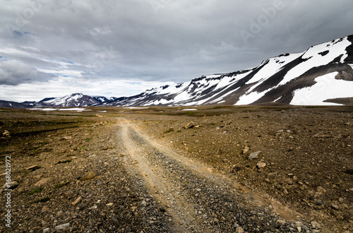 Traveling down a gravel road in snowy mountains of Iceland photo