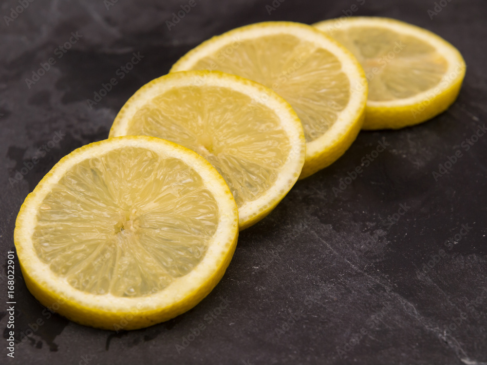 Four slices of lemon on slate wet stone Four slices of lemon on slate wet stone