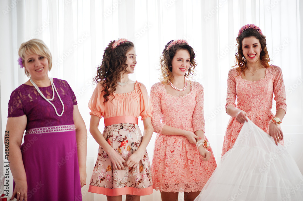Naklejka premium Bridesmaids and mother looking at bride while she is dressing up.
