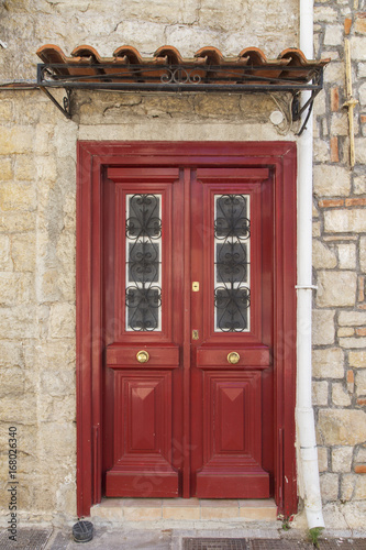 Vintage red wooden door in village of Greece