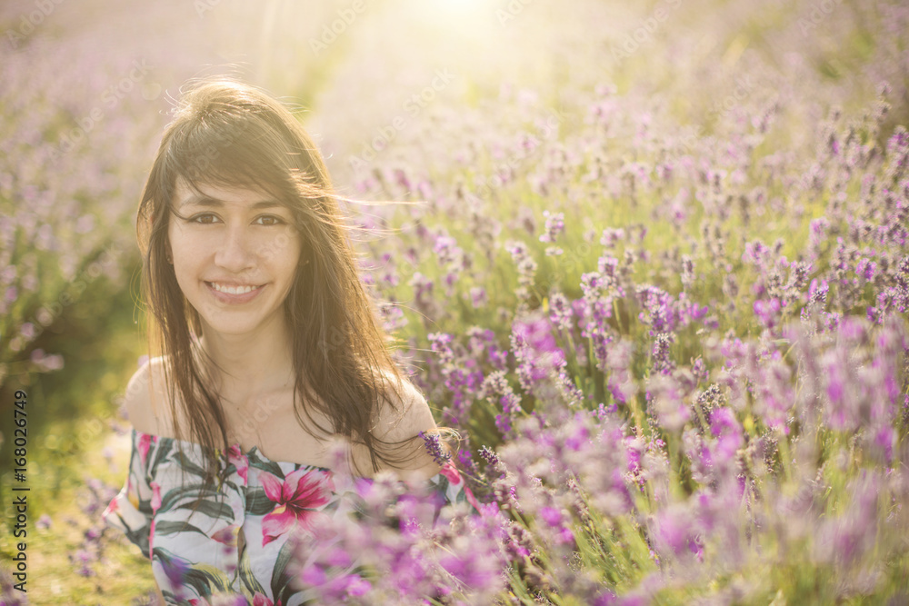 Naklejka premium Happy smiling Spanish Colombian woman is among the flowers of blooming lavender. Romantic mood photo