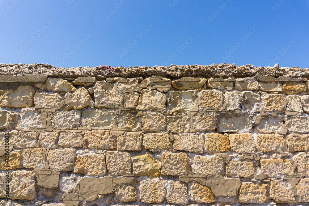 Alte Steinmauer vor blauem Himmel 