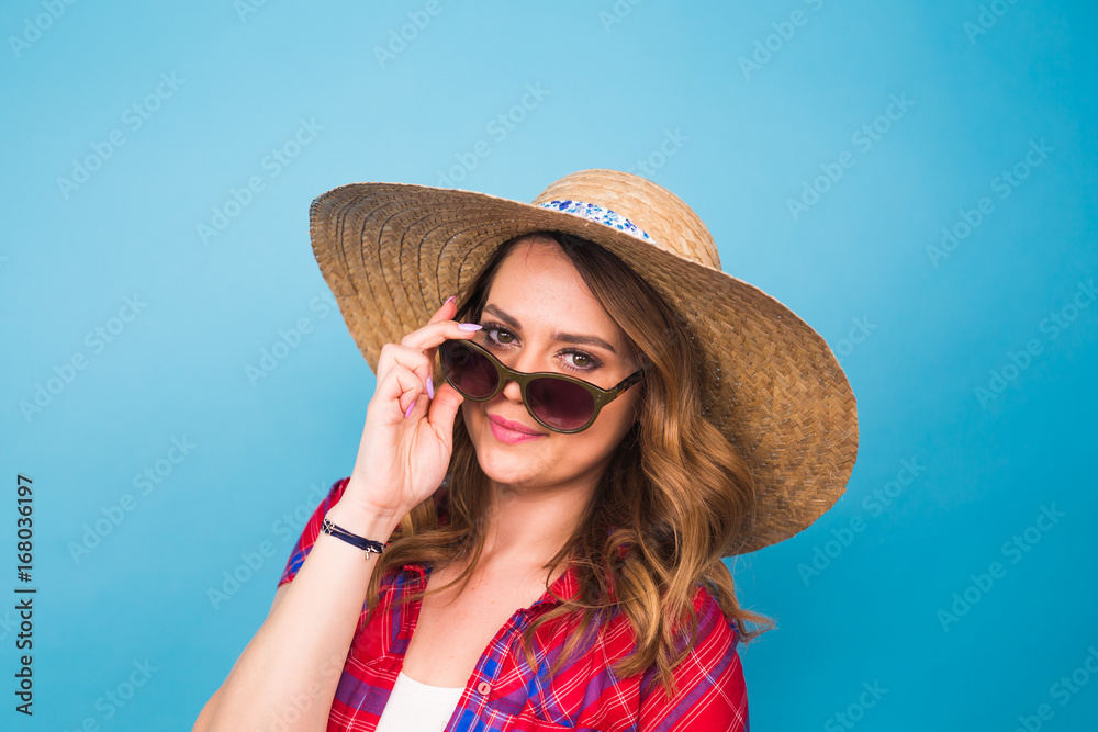 Holidays, summer, fashion and people concept - Girl in fashionable clothes straw hat. Portrait of charming woman on blue background with empty copy space