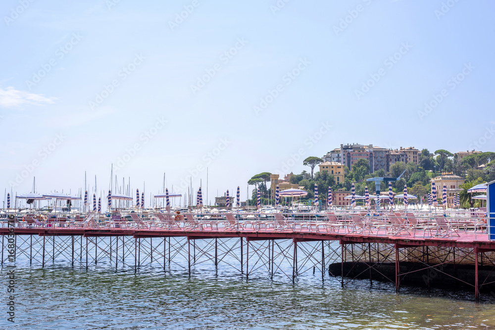 Beautiful view to Rapallo beach pier, blue sea and mountains. Italy beauties.