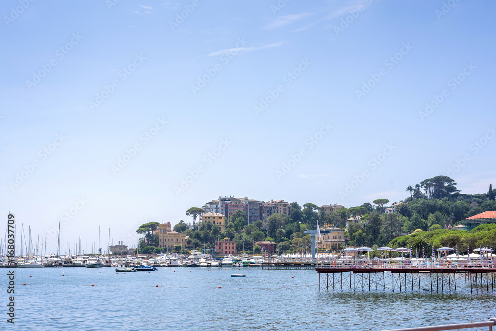 Daylight view to mountains, blue sea, beach pier and city of Rapallo, Italy.