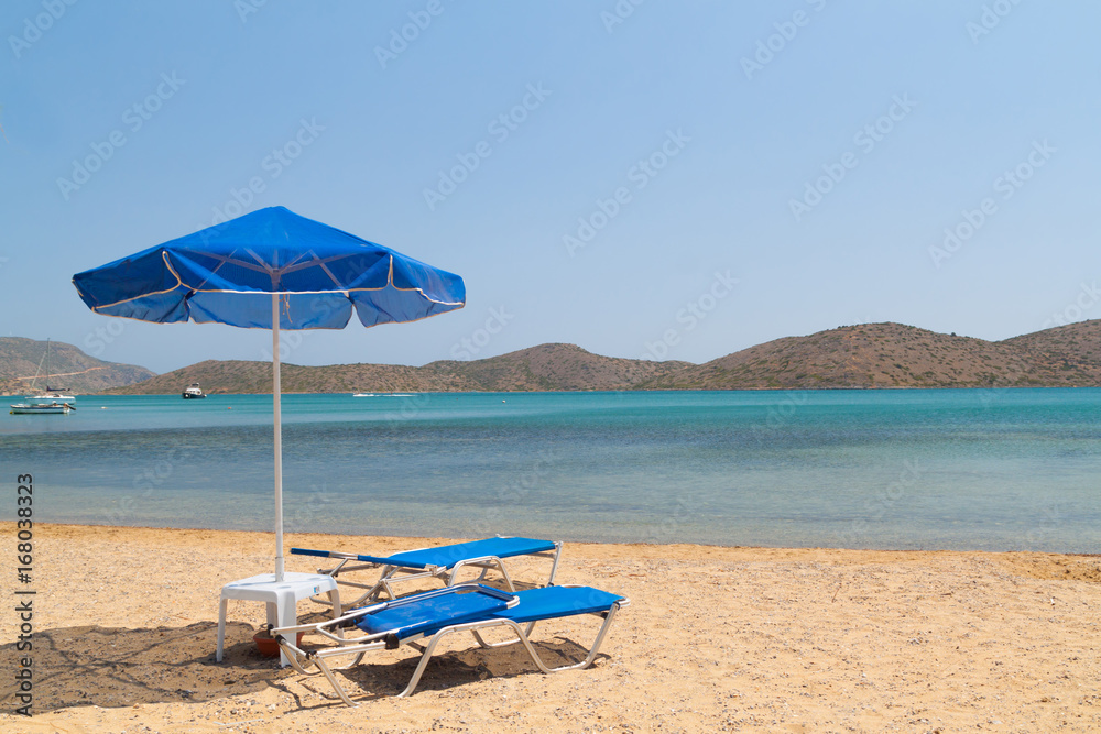 Blue deckchairs under parasol at Aegean Sea