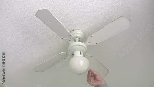 Domestic ceiling fan being switched on and starting to rotate, with its incorporated light fitting switched off.
