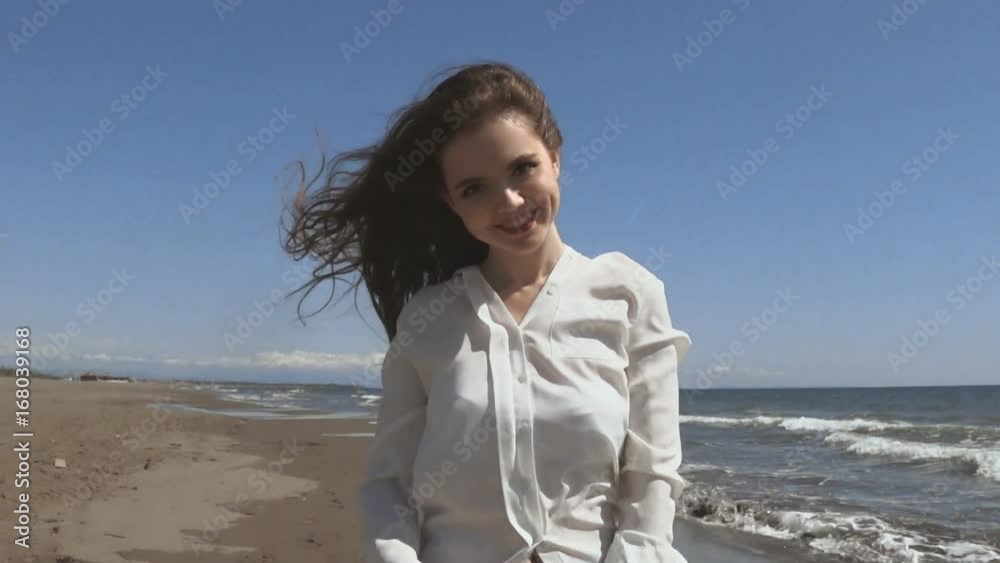 Beautiful young teen woman with blowing hair arms raised, brunette running on beach enjoying life, slow motion. Beautiful young teen woman with blowing hair arms raised, brunette running on beach enjoying life, slow motion.