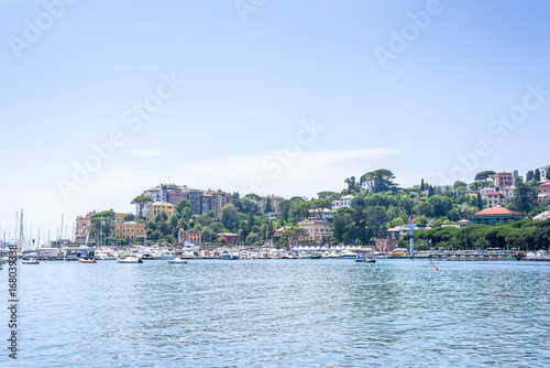 Daylight view to mountains, blue sea, beach pier and city of Rapallo, Italy.