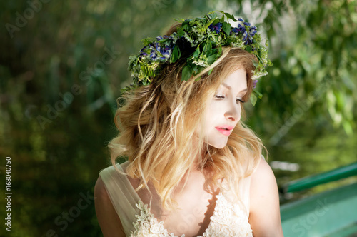 Portrait of woman with wreath sitting in boat with flowers. Summer photo