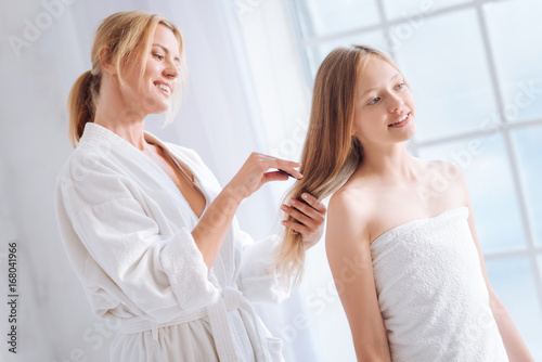 Cheerful woman combing clean hair