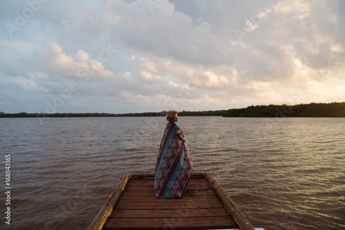 girl standing on dock while sunset