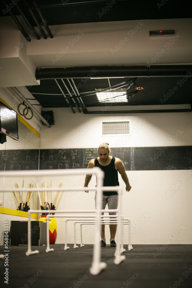 Fototapeta premium Young man jumping over obstacles in gym. Man in the gym.
